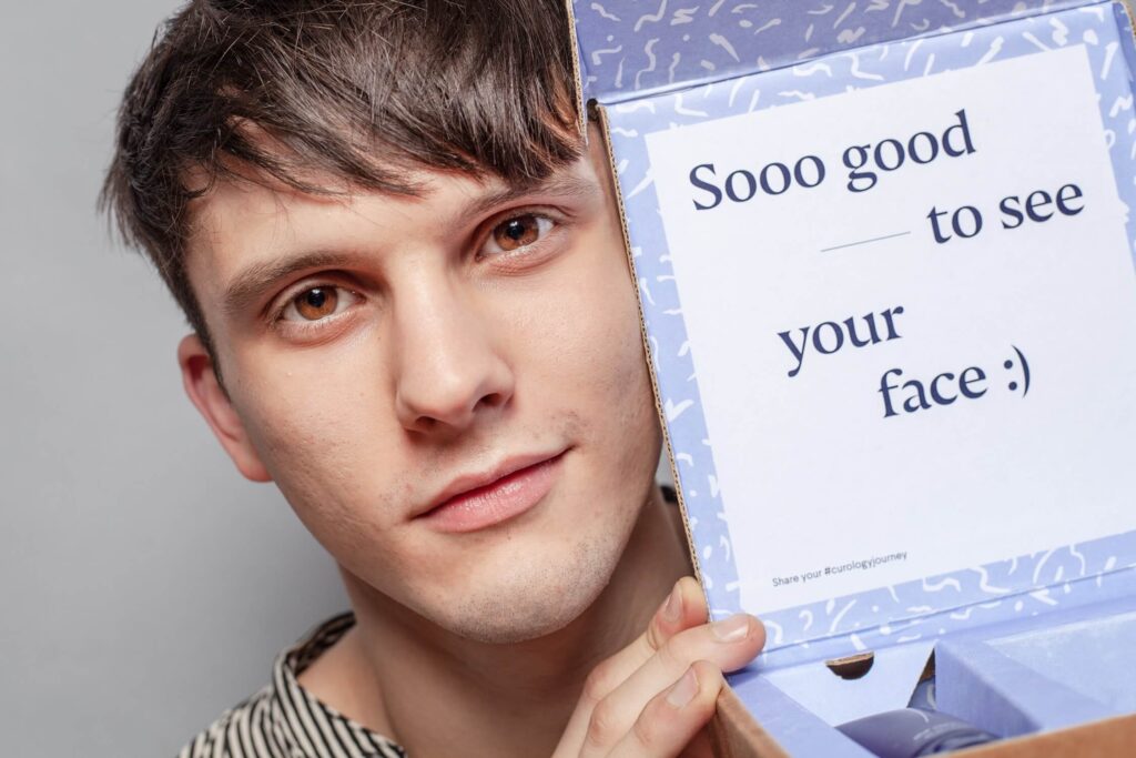 man holding up a box that says so good to see your face
