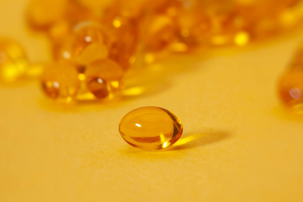 yellow supplement on a yellow backdrop with other vitamins behind