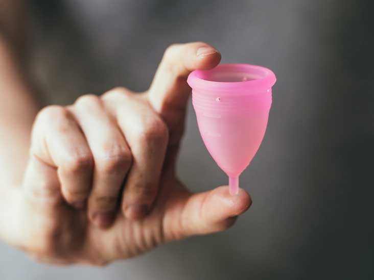 woman holding a pink menstrual cup