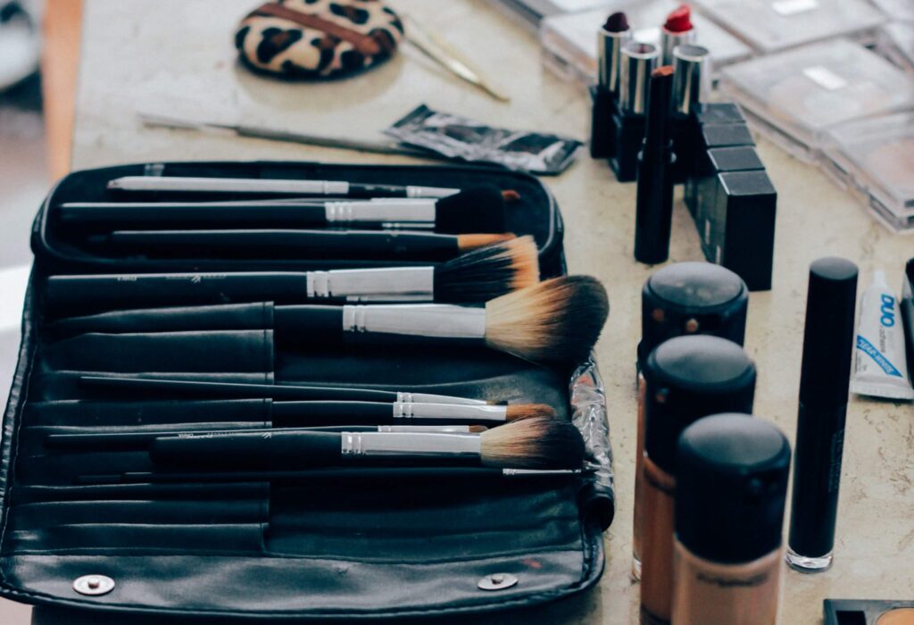 a counter with makeup brushes in a case next to open makeup products including foundation and lipstick