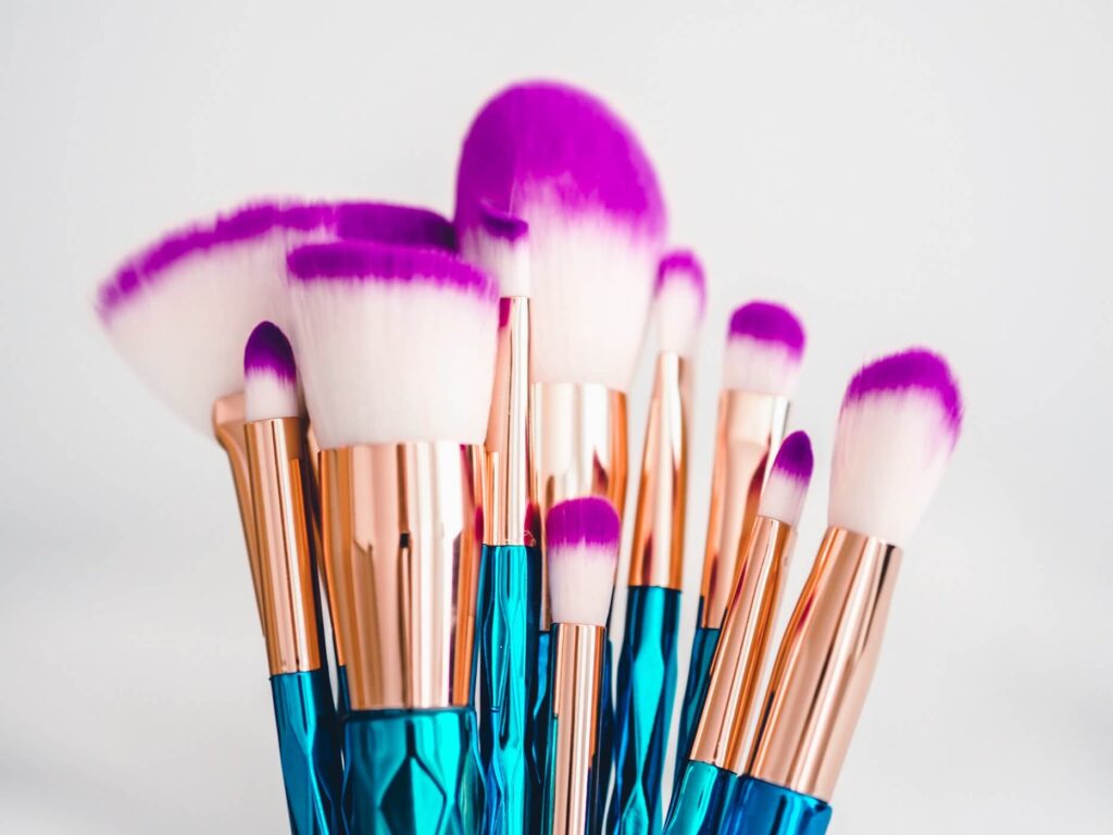 makeup brushes with turqouise and gold handles and white and purple bristles