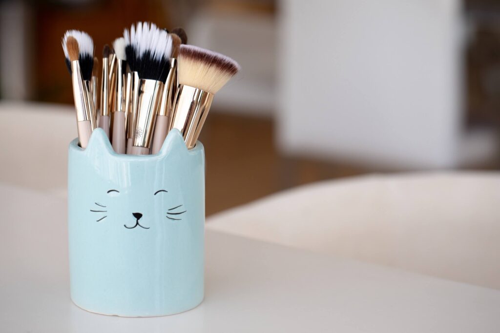 ceramic blue jar with a cat face containing several makeup brushes