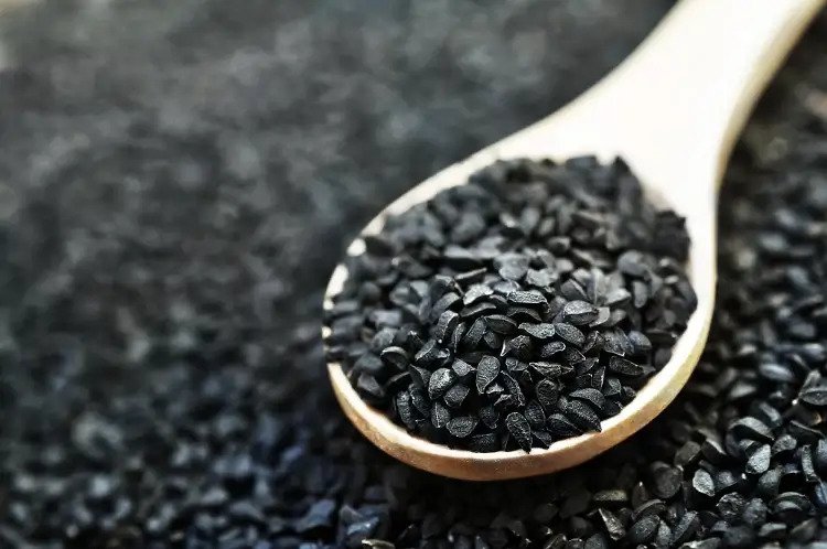 flat lay of black seeds in a wooden sppon