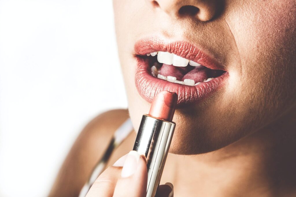 Close up of woman applying pink lipstick to her lips