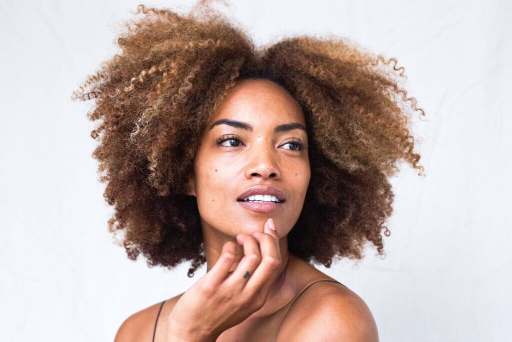 Black woman with curly brown medium length hair looking into the distance