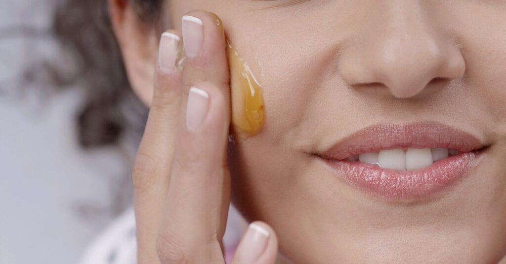 front view of a woman smearing honey on her cheek