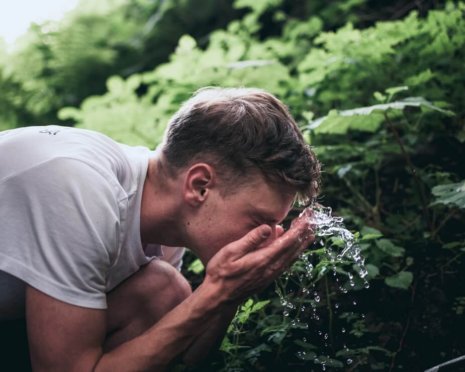 young man washing his face with water