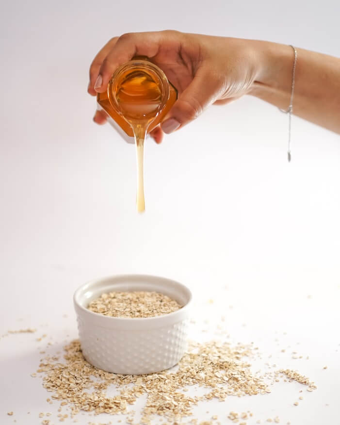 hand pouring out honey on a bowl of oats