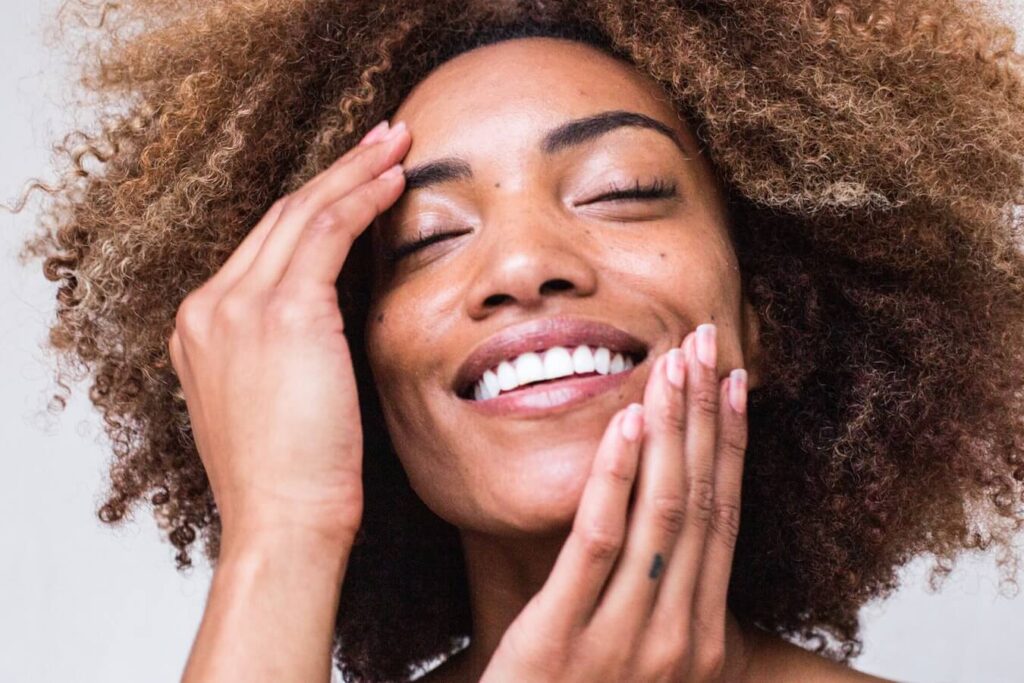 young woman happily touching and feeling her face