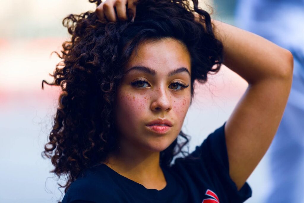 young woman with freckles on her cheeks showing camera