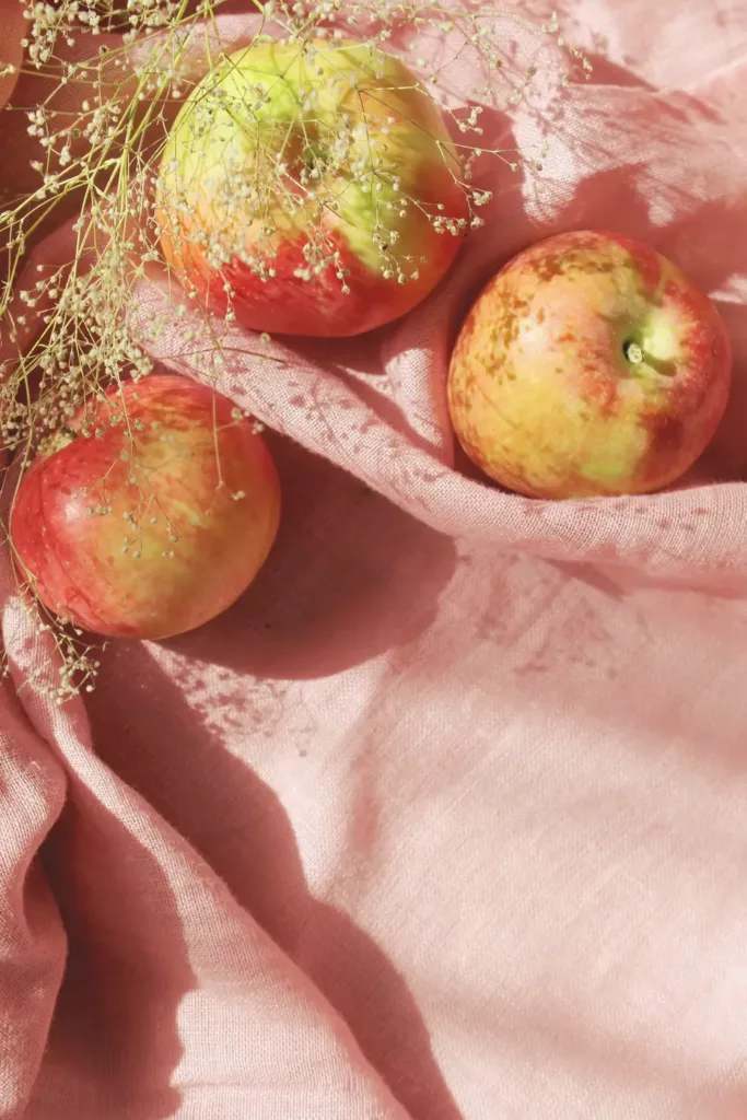 three apples placed on a pink cloth