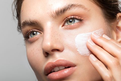 a woman applying cream on her face