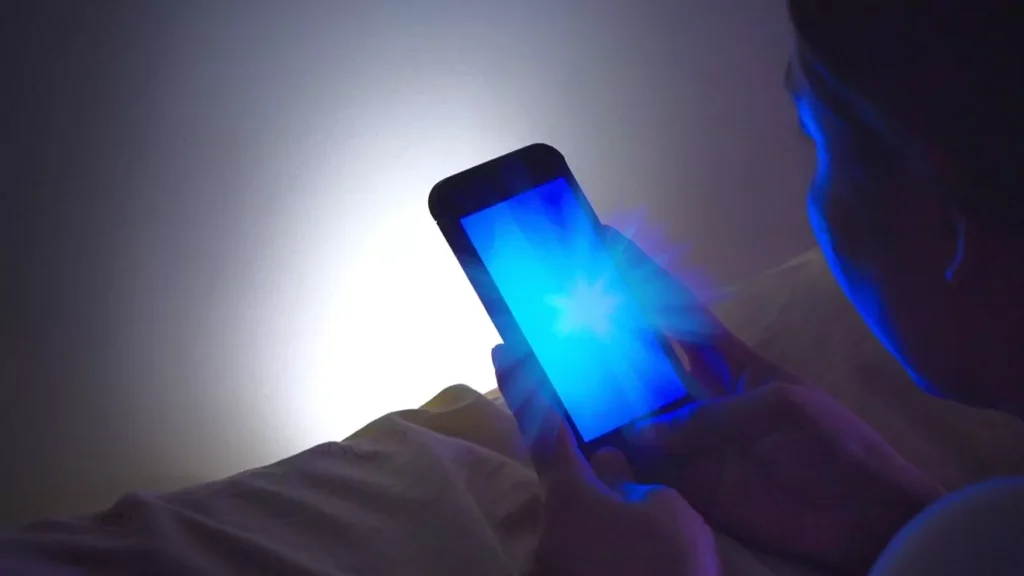 a person holding a phone with blue light skin damage