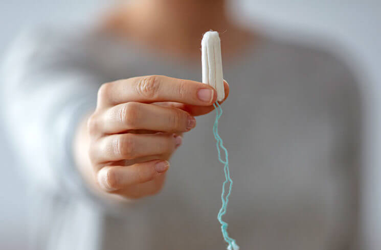 a woman holding a tampon and Toxic Shock Syndrome