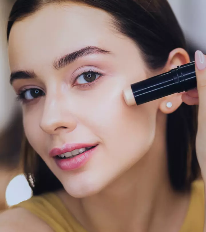 a woman applying concealer on her cheek